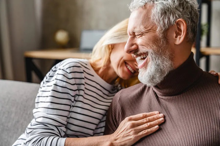 A mature couple laughing together at home, the kind of comfortable, confident smiles comprehensive dental care helps the West Valley keep, at Copper Sky Dental in Peoria, AZ