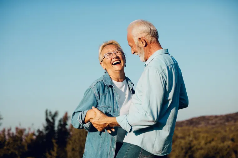 An active, laughing senior couple outdoors, the kind of vibrant Sun City residents Copper Sky Dental has cared for since 1976