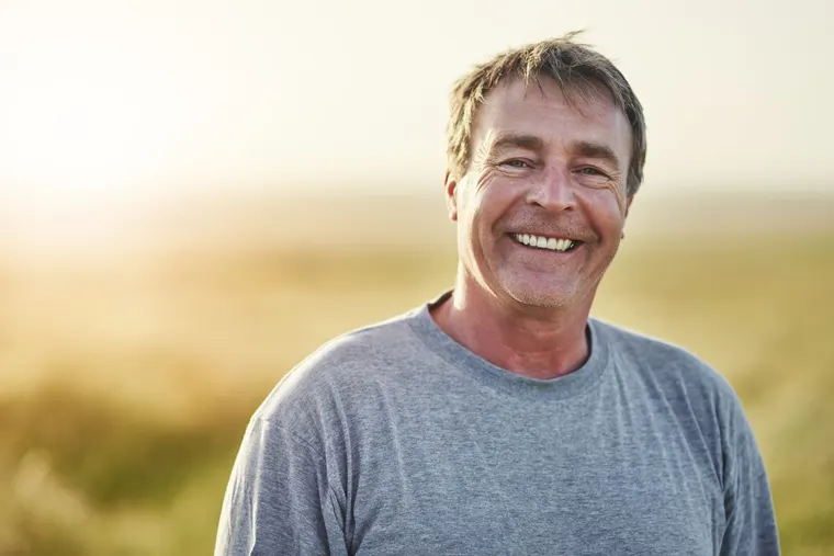 A smiling man outdoors at golden hour, representing the new and established Surprise, AZ residents Copper Sky Dental welcomes